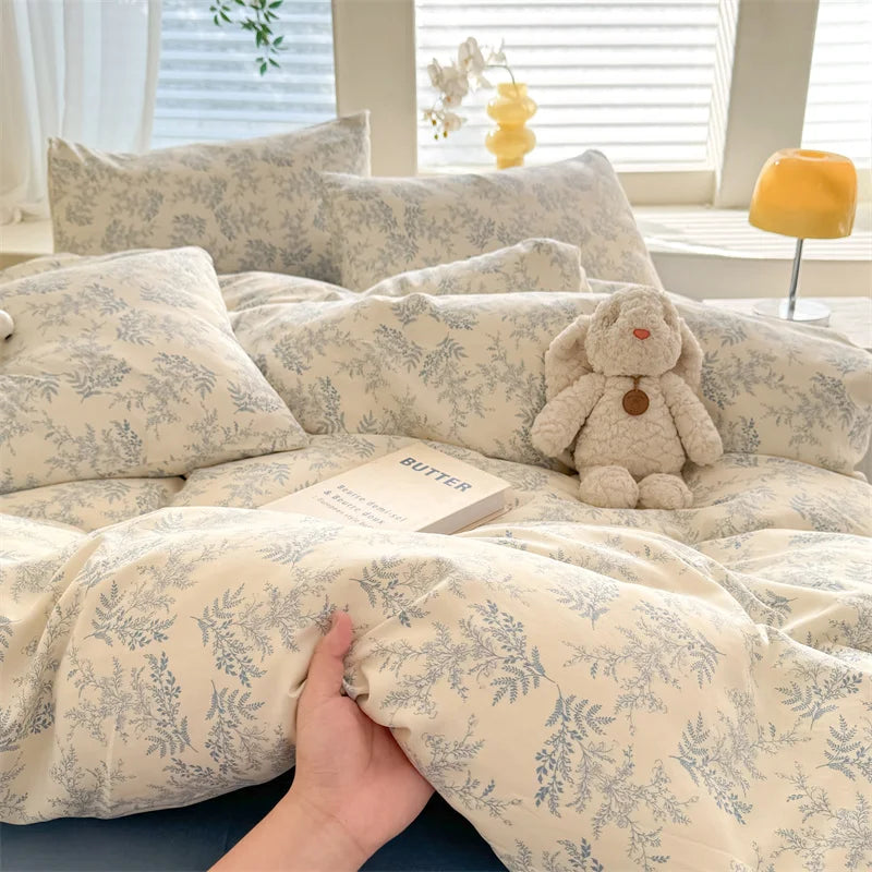 A beige and gray floral print duvet cover set with pillows is shown on a bed.