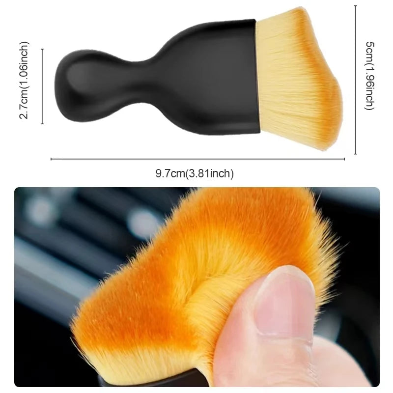 A close-up of an orange soft-bristle cleaning brush with a protective case being held by a hand.