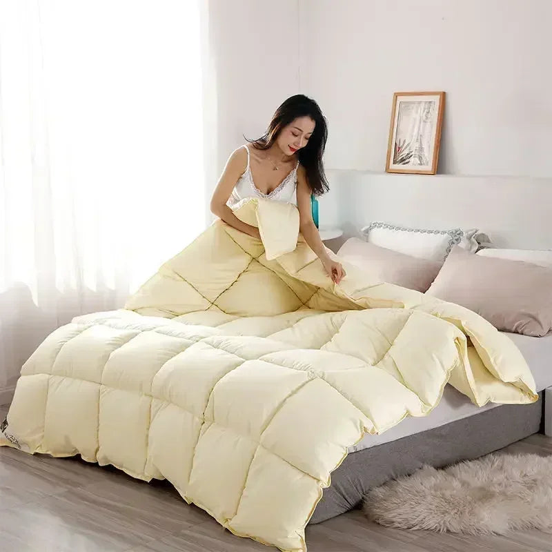 A fluffy cream-colored goose and duck down comforter with a cotton cover displayed on a bed.