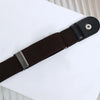 A close-up view of a black elastic belt strap with a silver buckle, laid on a white surface.