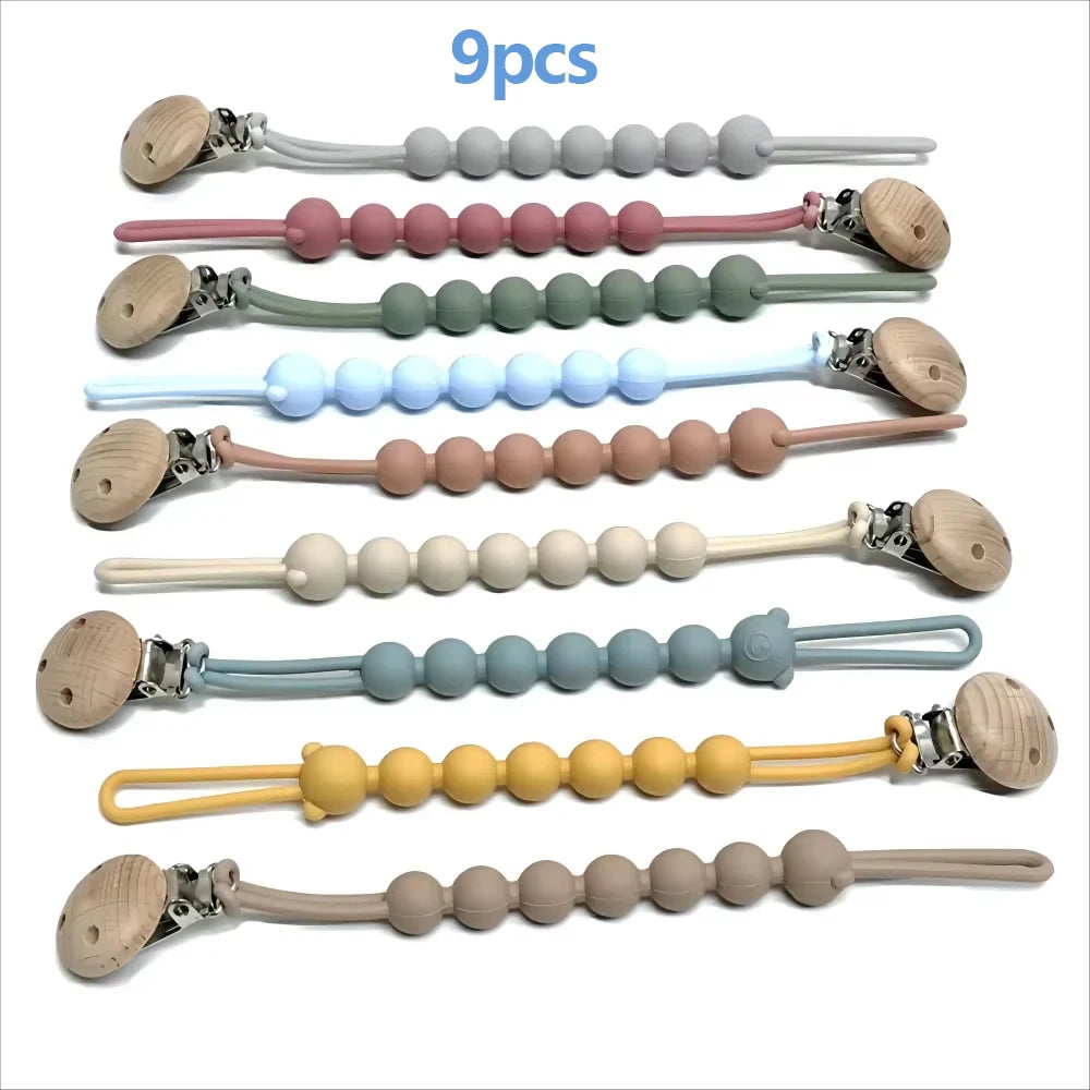 Nine silicone pacifier clips in various pastel colors and natural tones displayed horizontally.