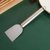 A stainless steel multi-purpose scraper with a handle is shown against a dark green background.