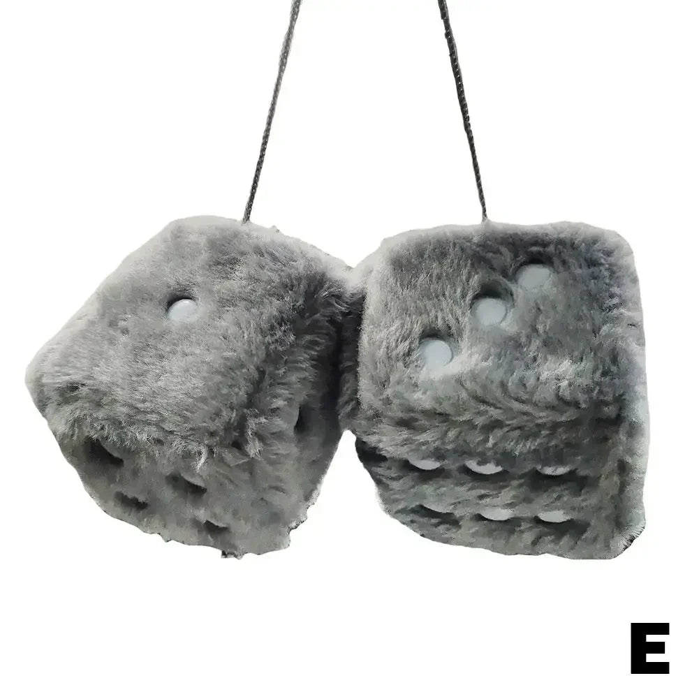 A pair of gray plush velvet dice car mirror pendants hanging by strings.
