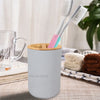 A white bamboo bathroom organizer set featuring a soap dispenser and two toothbrushes is shown on a wooden surface.