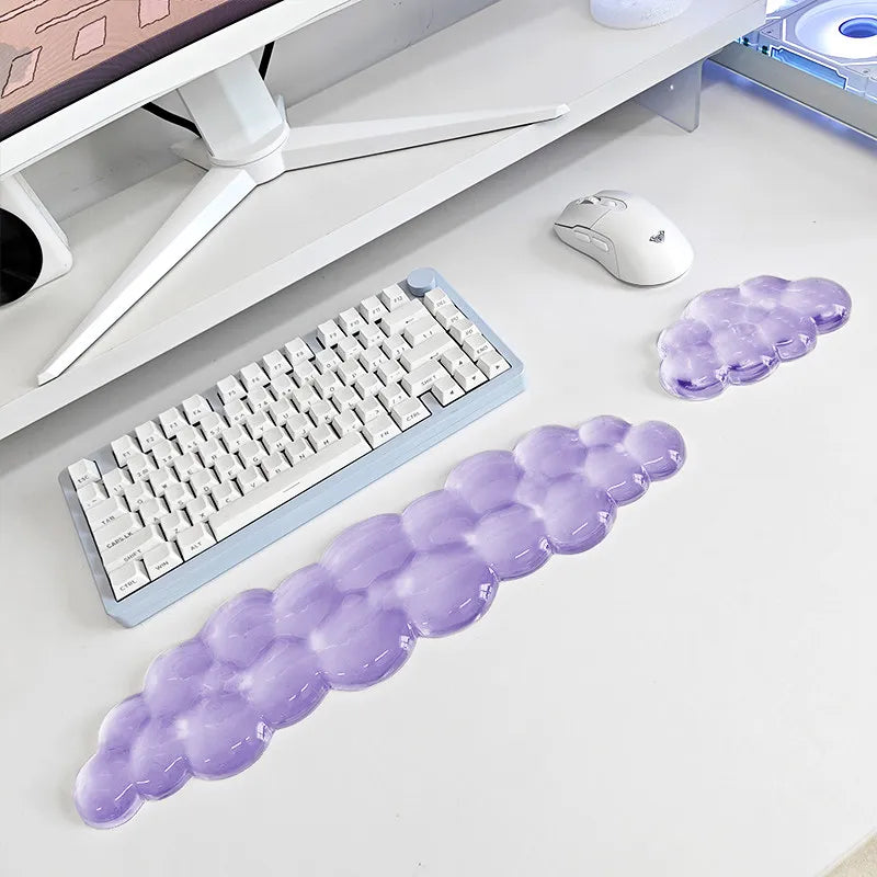 A set of translucent purple cloud-shaped ergonomic wrist rests for a keyboard and mouse are displayed on a white desk.