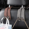 A close-up of a black car seat with two metal hooks used to hang a white shopping bag and a plaid fabric item.