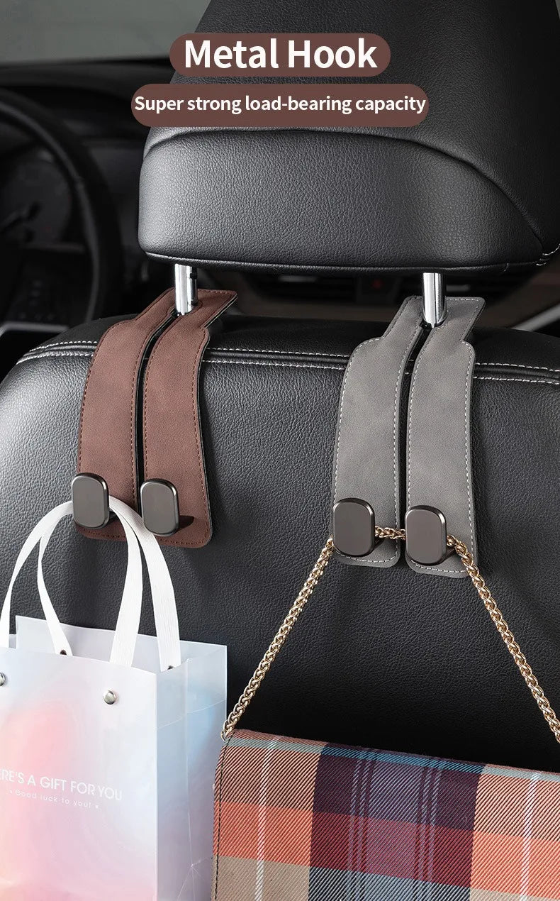 A close-up of a black car seat with two metal hooks used to hang a white shopping bag and a plaid fabric item.