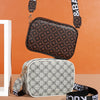 A brown patterned compact crossbody bag is displayed against an orange background, with a gray patterned bag and black straps