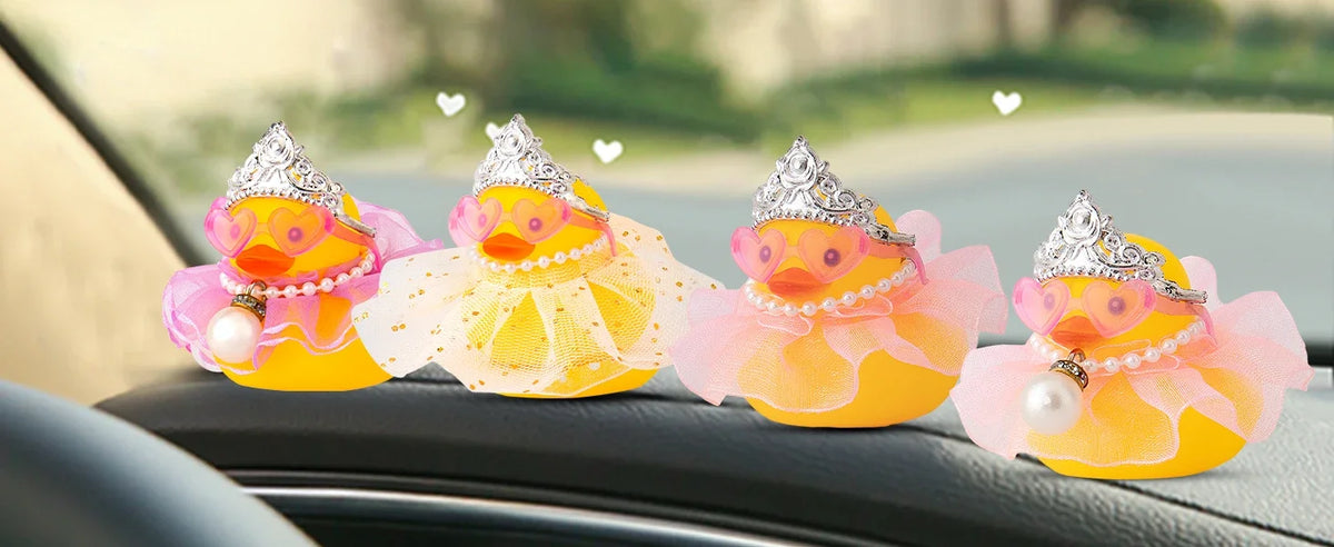 A collection of colorful rubber duck decorations with crowns, sunglasses, and pearl necklaces displayed on a car interior.