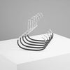 A silver metal hanger with multiple curved hooks resting on a white surface.