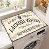 A laundry room featuring a white washing machine with a decorative mat on top, next to a window.