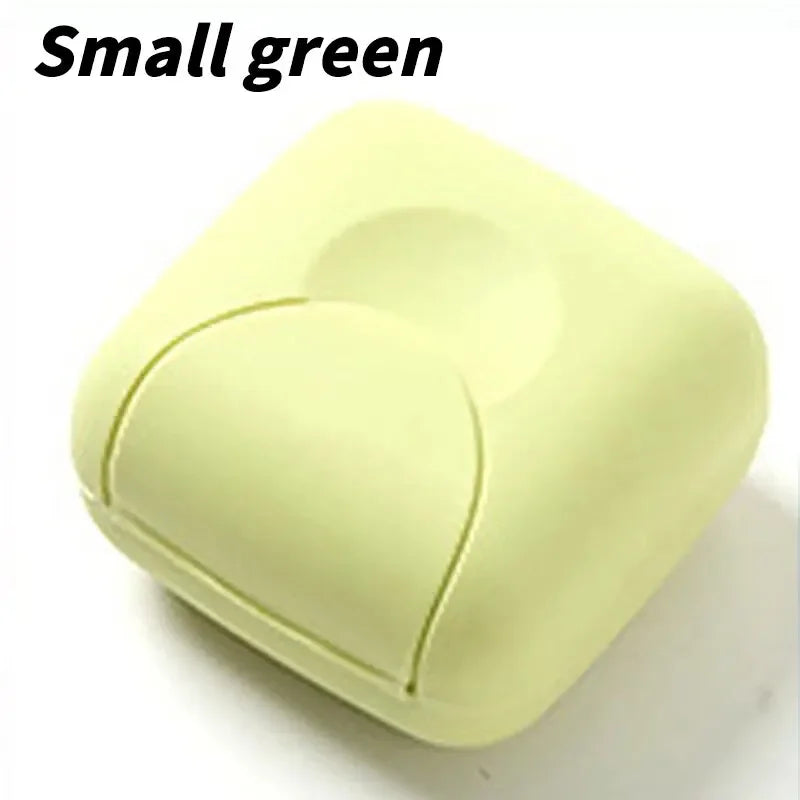 A small, light green, square-shaped portable soap holder with a rounded top and a visible seam.
