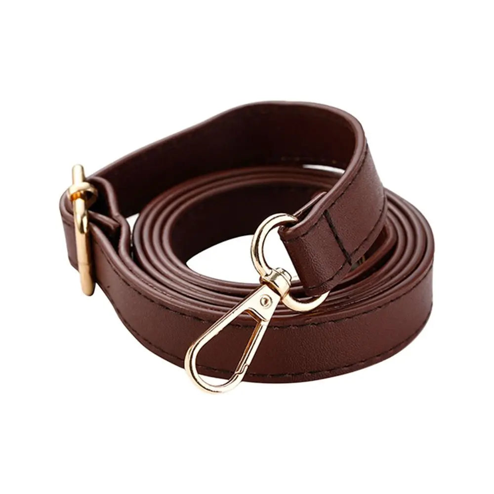 A brown leather strap with a gold-toned buckle is shown coiled and laid out.