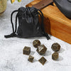 A black leather drawstring pouch next to a set of bronze metal polyhedral dice.