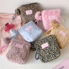A collection of vintage leopard print cosmetic bags in various shades of pink and brown, including fuzzy and textured materia