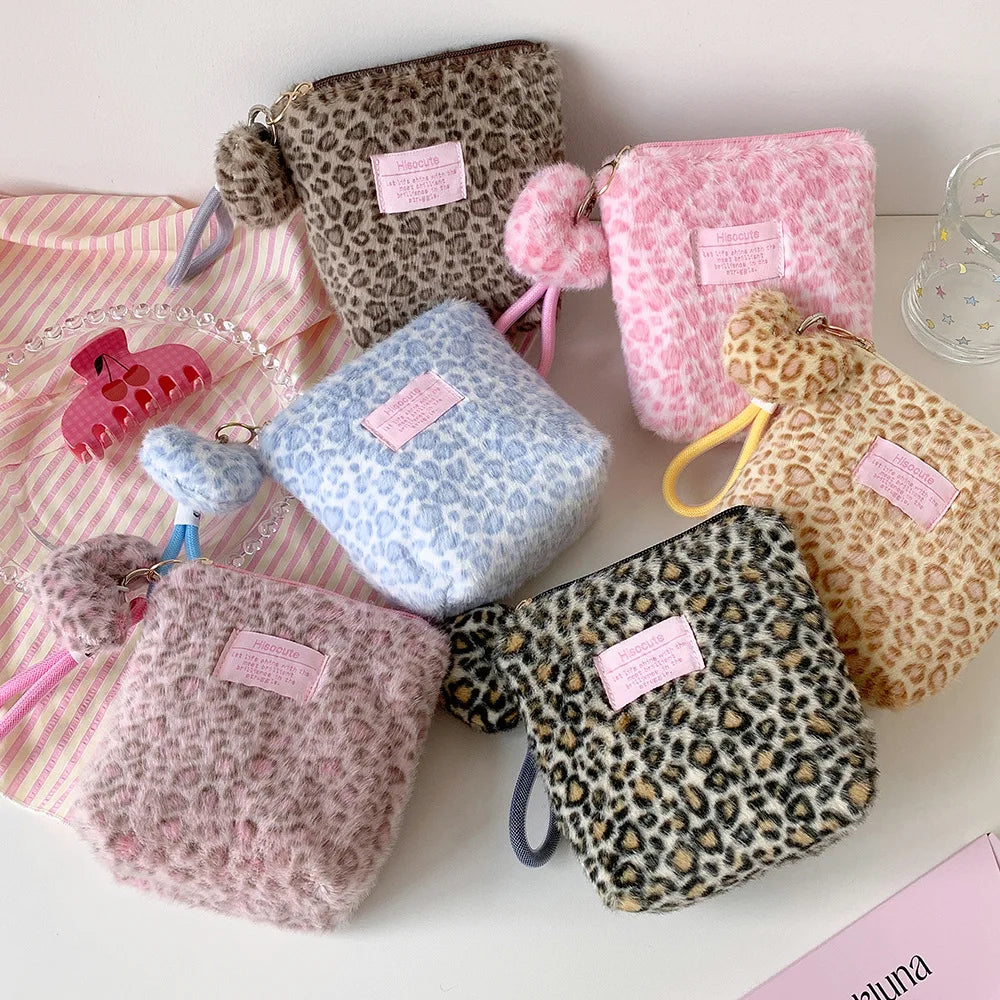 A collection of vintage leopard print cosmetic bags in various shades of pink and brown, including fuzzy and textured materia