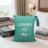 A teal laundry bag with the word LAUNDRY and Bag printed on it, resting on a white bed.