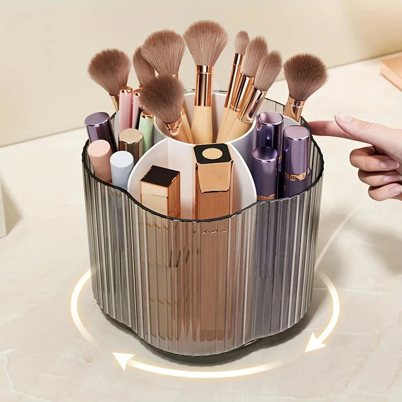 A silver rotating brush holder filled with six makeup brushes and cosmetic tubes in various shades of pink, gold, and purple.