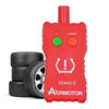 A red 2-in-1 TPMS relearn tool with TX and LOWBAT indicators lying next to a stack of tires.