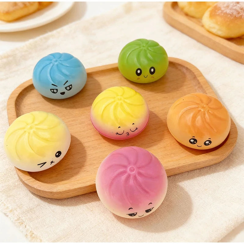 A set of colorful squishy stress relief toys shaped like cute faces in various pastel colors on a wooden tray.