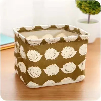 A square storage basket made of cotton and linen with a olive green and white textured pattern.