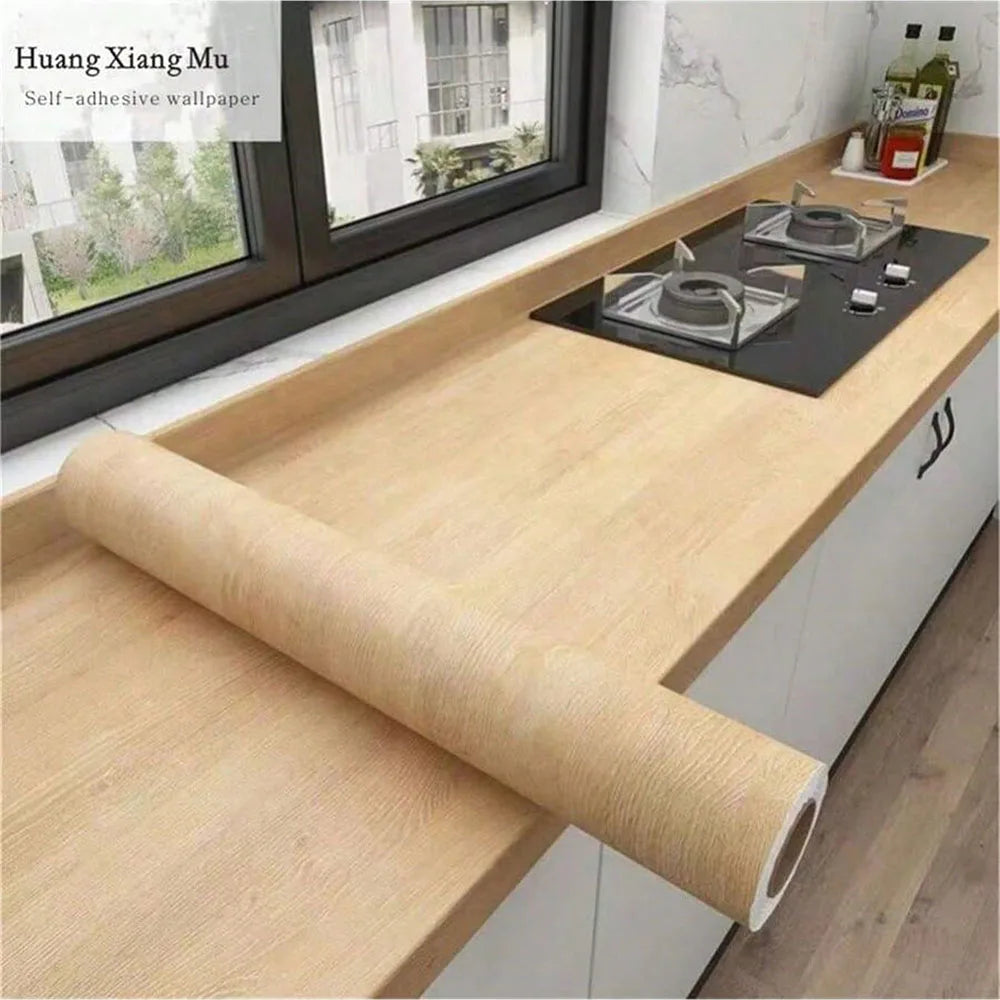Roll of self-adhesive wood grain waterproof wallpaper next to a window with a dark countertop.
