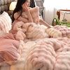 A close-up of a pink and cream ultra-soft plush bedding set featuring faux fur pillows and blankets.