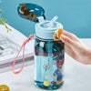 A hand holds a blue cartoon straw water bottle with a clear lid and a pink cord, featuring a teddy bear design.