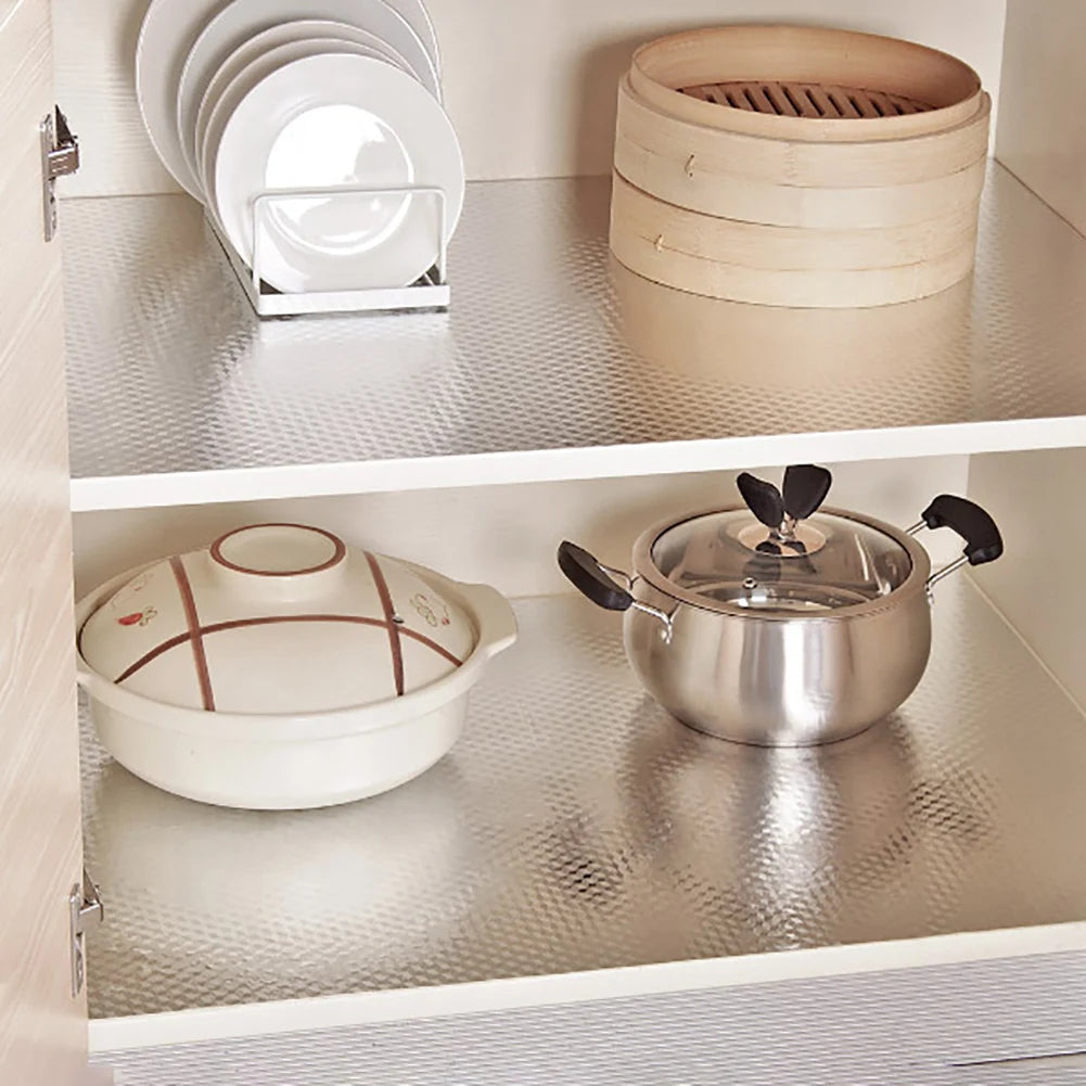 A set of white plates and a stainless steel pot are displayed on a kitchen shelf.