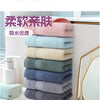 A stack of six pink, blue, and gray premium pure cotton face towels displayed next to a mirror.