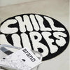 A round black carpet with white lettering spelling out CHILL LUBES