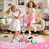 A young girl is singing into a pink microphone stand with a built-in speaker in a living room setting.
