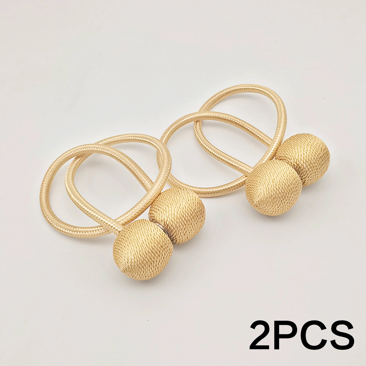 Deux attaches magnétiques en forme de boule minimalistes de couleur or sur fond blanc.