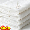 Stack of white sheer tulle fabric with pearl embellishments, used as a table runner.