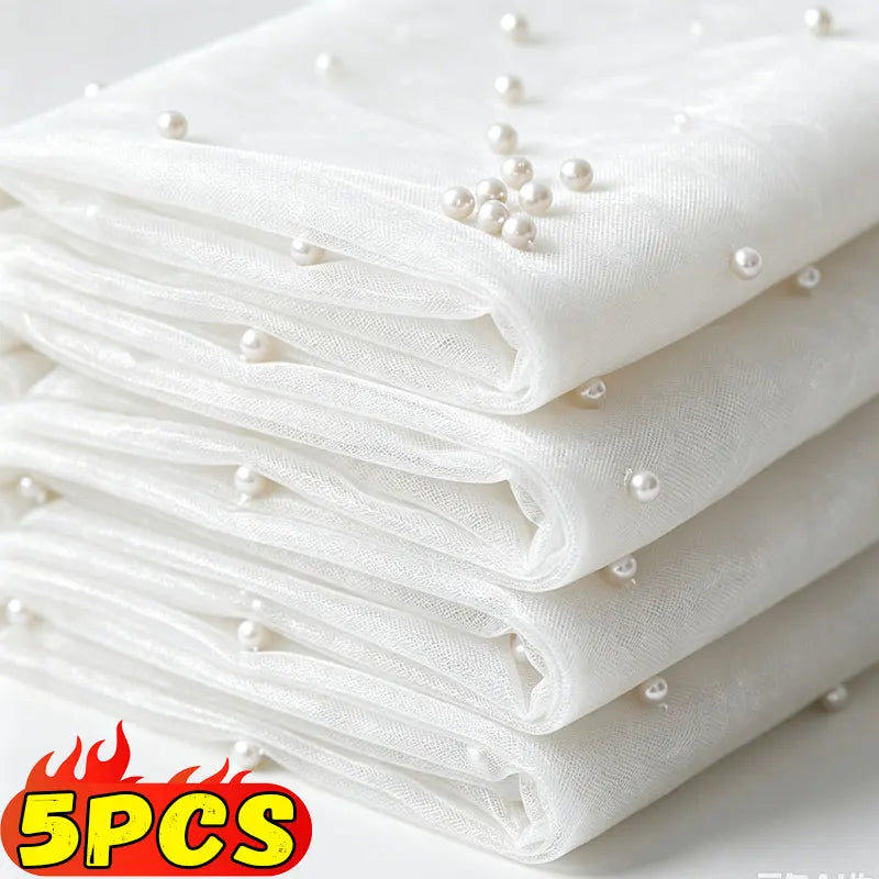 Stack of white sheer tulle fabric with pearl embellishments, used as a table runner.