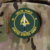 An embroidered patch for the Delta Force, featuring a stylized dagger within a circle on a camouflage uniform.