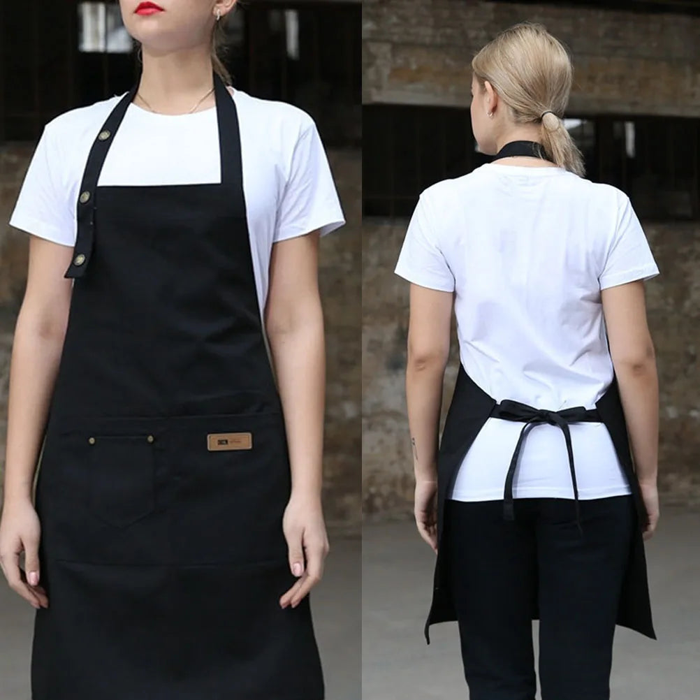 A woman wearing a black canvas kitchen apron over a white t-shirt and black pants.