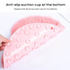 A pink suction cup foot massage mat with exfoliating bristles is shown being held by a hand.