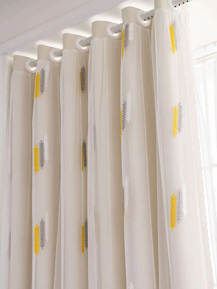 Elegant cream curtains with yellow and gray wheat embroidery hanging from a white rod.