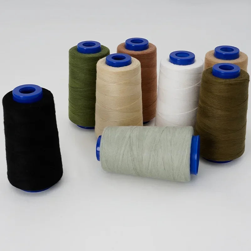 A collection of spools of heavy-duty polyester thread in various colors including olive green, beige, white, and brown.