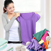 A woman holds up a purple natural wool dryer ball garment while surrounded by other colored fabric and dryer balls.