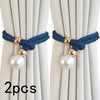 A set of two blue rope curtain tie-backs with gold accents and pearl-like spherical beads against a light fabric background.