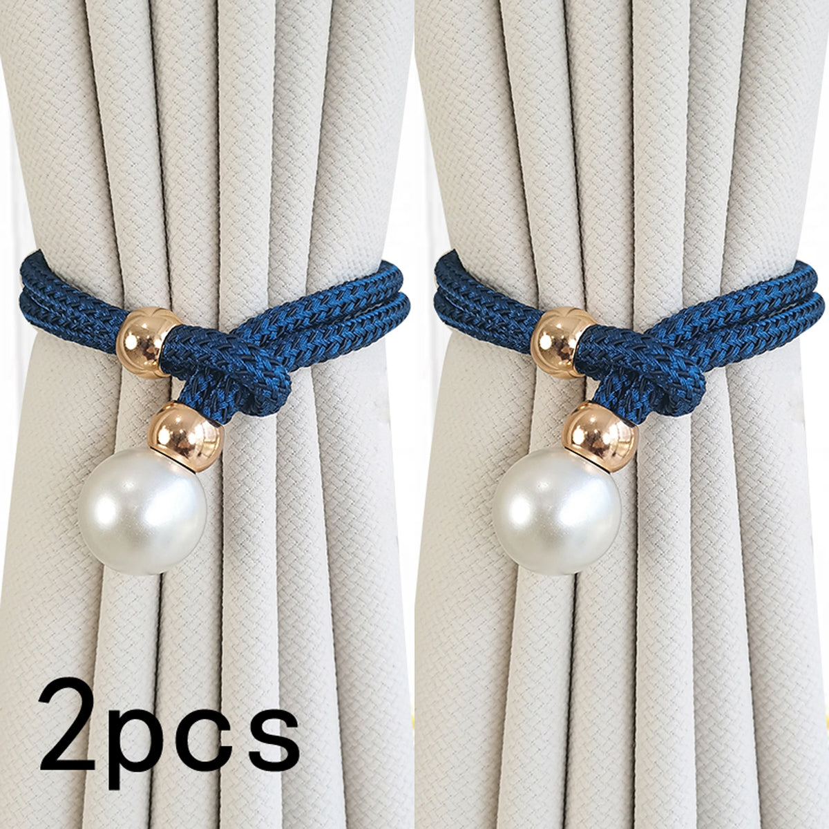 A set of two blue rope curtain tie-backs with gold accents and pearl-like spherical beads against a light fabric background.