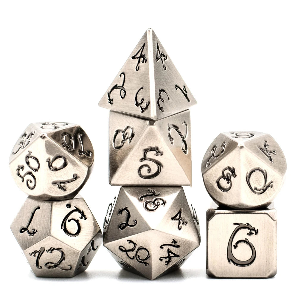 A set of seven metal polyhedral dice featuring a dragon font design, including a tetrahedron and a cube.