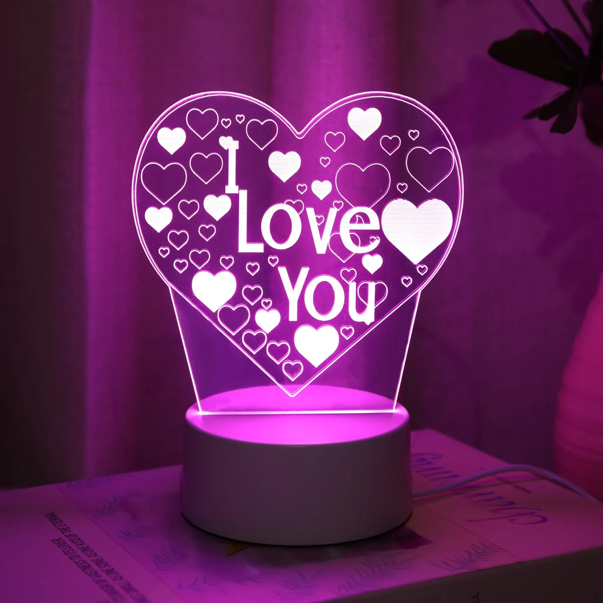 A glowing pink LED heart night light with a 3D design featuring the words I Love You surrounded by small hearts.