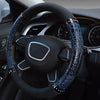 A close-up view of a black car steering wheel with blue crocodile grain leather covers.