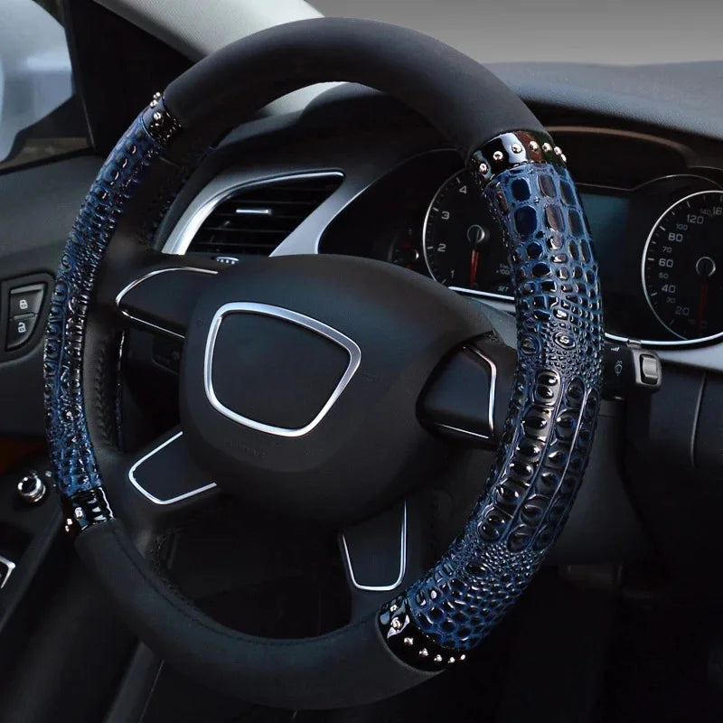 A close-up view of a black car steering wheel with blue crocodile grain leather covers.