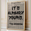 A framed print featuring a black and white newspaper layout with the text It's already yours from The Universe
