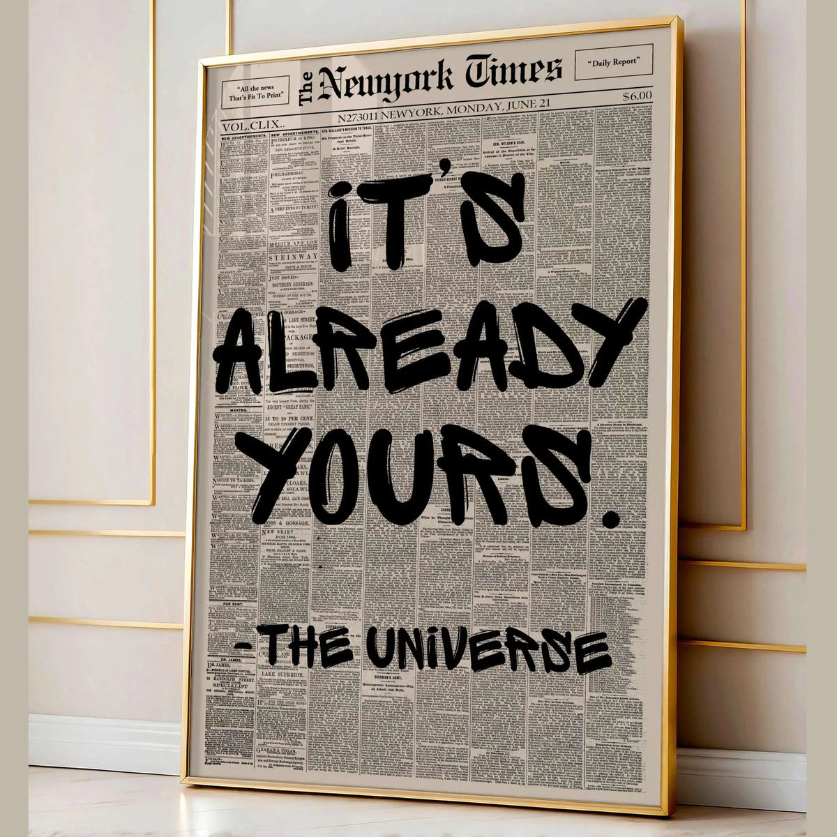 A framed print featuring a black and white newspaper layout with the text It's already yours from The Universe