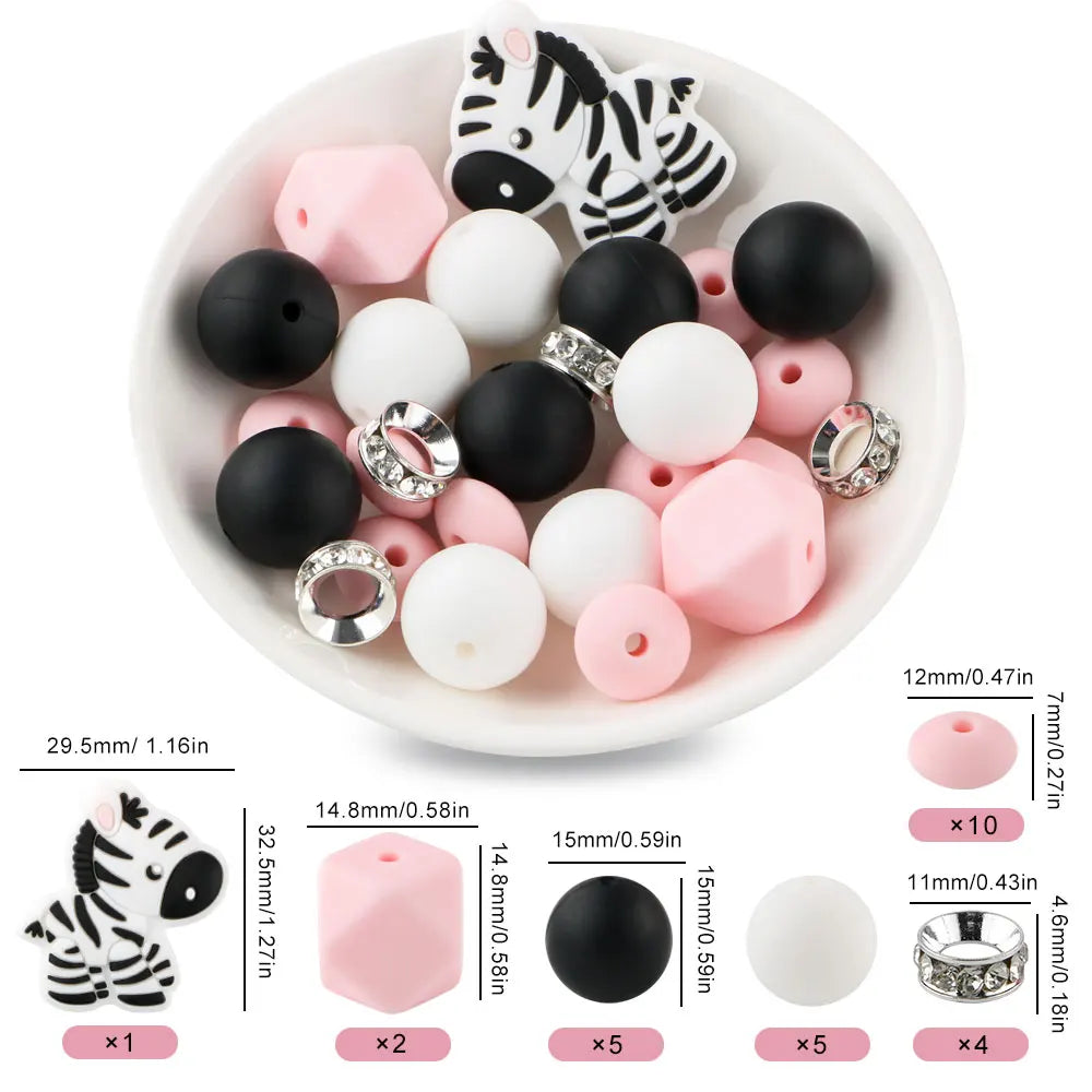 A white bowl filled with black and pink silicone focal beads shaped like tigers and other cartoon animals for jewelry making